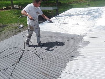 worker painting large metal canopy roof